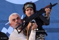 Pemimpin Hamas Yahya Sinwar menggendong anak seorang pejuang Brigade Al-Qassam, yang tewas dalam pertempuran baru-baru ini dengan Israel, selama rapat umum di Kota Gaza pada 24 Mei 2021. (Foto: Tangkapan Layar)